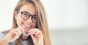 young girl holding her Invisalign clear aligners