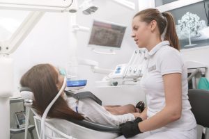 Dentist speaking to a patient wearing an inhalation sedation mask in a modern dental office, emphasizing patient-centered care and comfort during treatment.