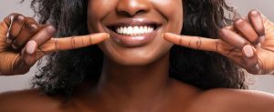 young woman pointing to her smile