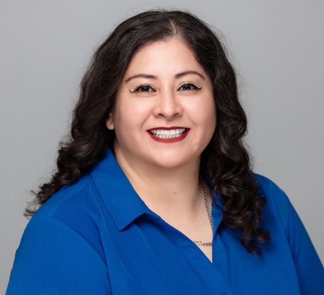 Cristina, Treatment Coordinator at Robles Family Dental, smiling in a blue shirt against a gray background.