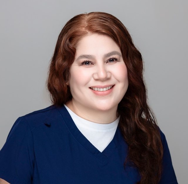 Yesenia, dental assistant at Robles Family Dental, smiling in navy scrubs, professional portrait.