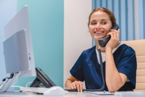 Dental assistant speaking on the phone at Robles Family Dental, providing information about dental care and insurance options.